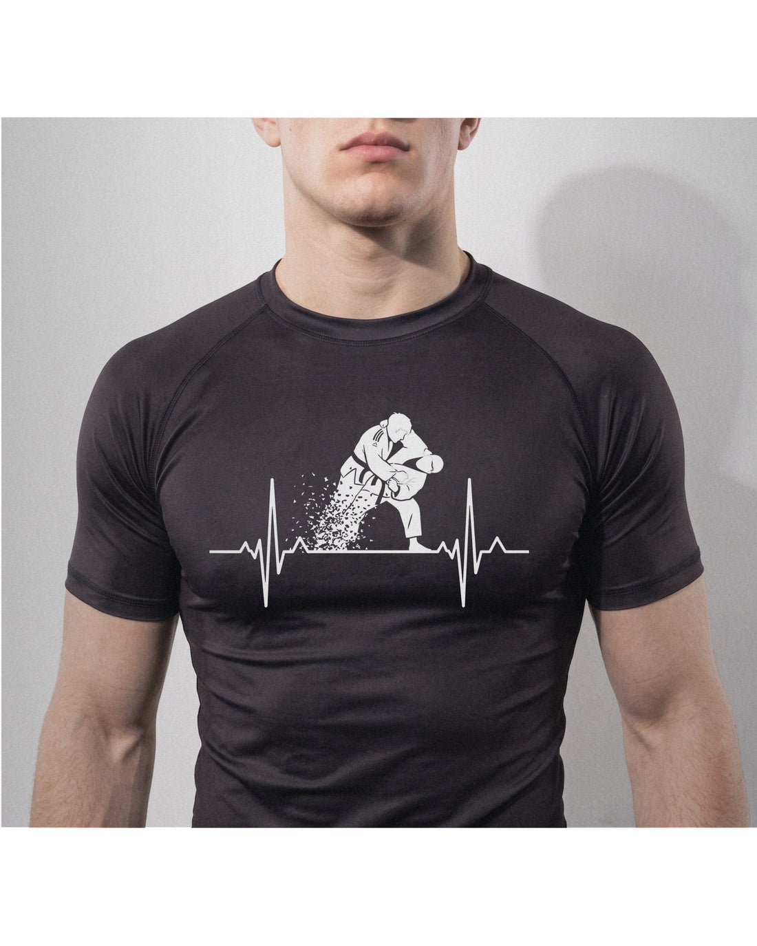 Grappler wearing the black Kuzushi Pulse Rashguard with a heartbeat line breaking into a jiu-jitsu throw across the chest